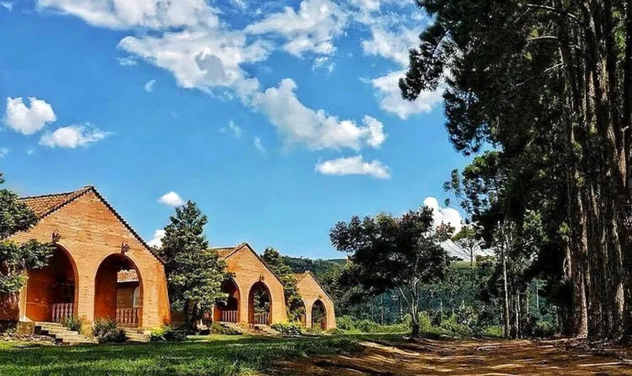 Chalés de tijolo com arcos, entre o gramado e as árvores